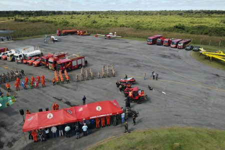Aerial view of firefighter training with vehicles, tents, and personnel outdoors.