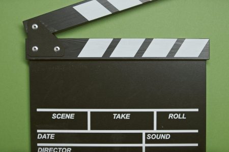 A classic film clapperboard on a green surface, essential for movie scenes.