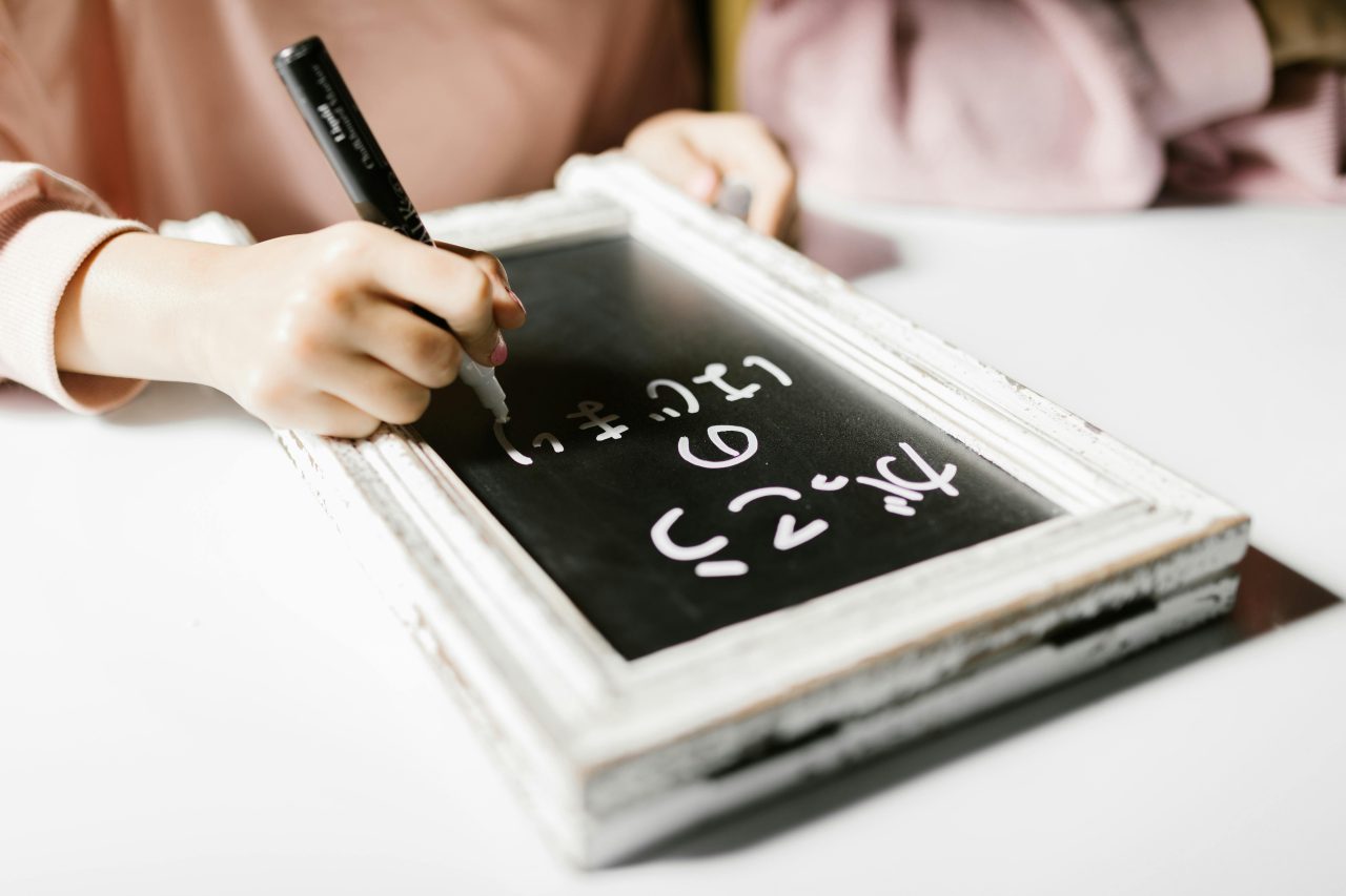 Child writing on a small chalkboard, exploring creativity and education indoors.